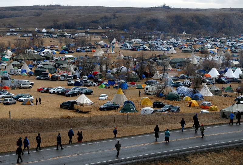 Protesters — or water protectors, as they identify themselves — walk along Highway 1806, past a sprawling encampment at Standing Rock on Thursday. Thousands of people gathered to join the Standing Rock Sioux Tribe's protest of the Dakota Access Pipeline. Photo/Jessica Rinaldi/Boston Globe/Getty Images